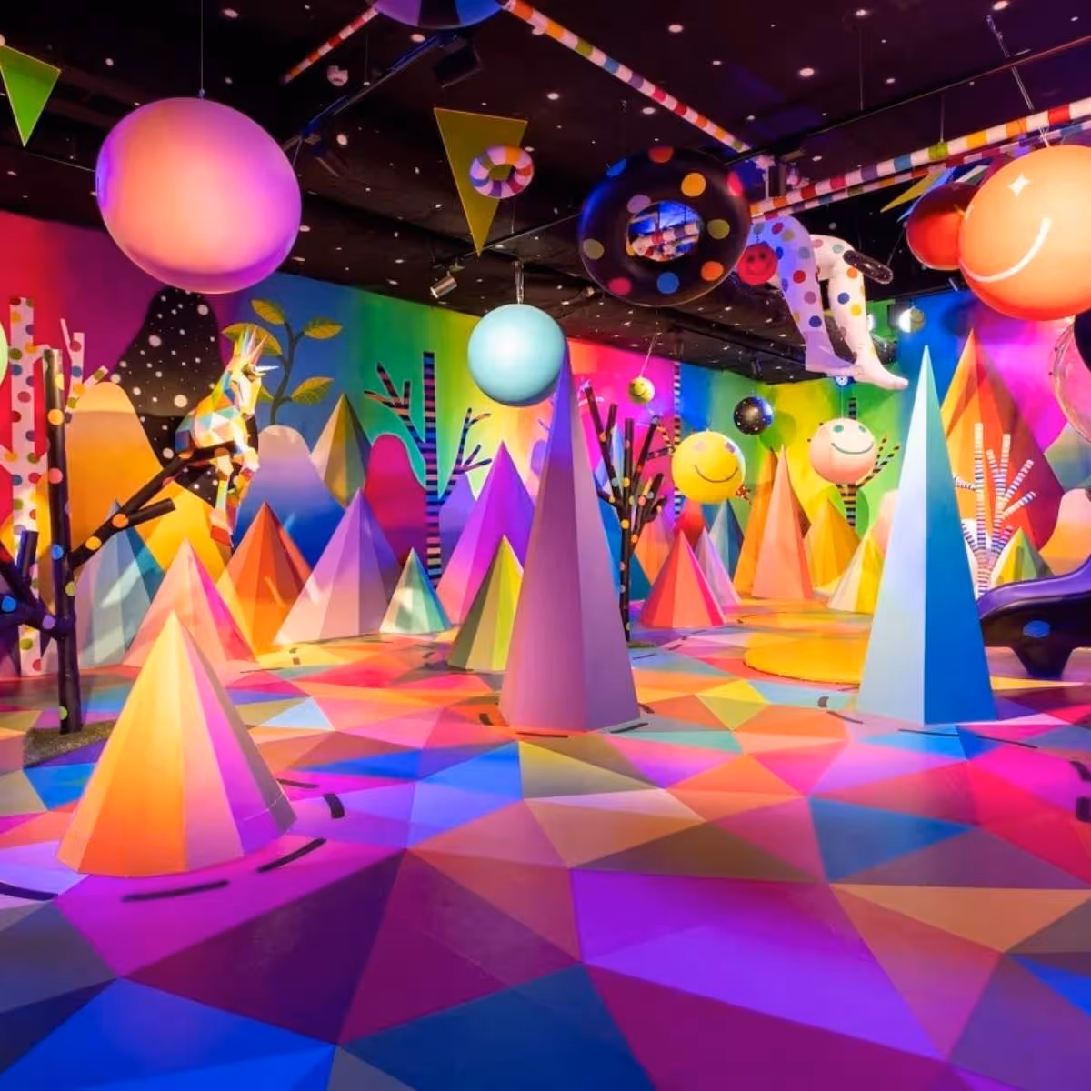Espacio colorido con formas geométricas, globos y árboles abstractos