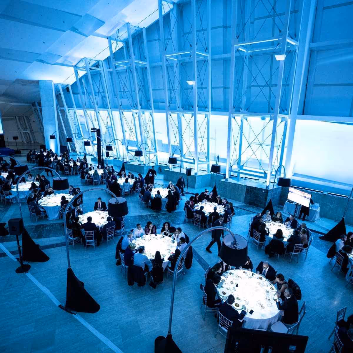 Evento corporativo con mesas redondas en un moderno edificio azul iluminado