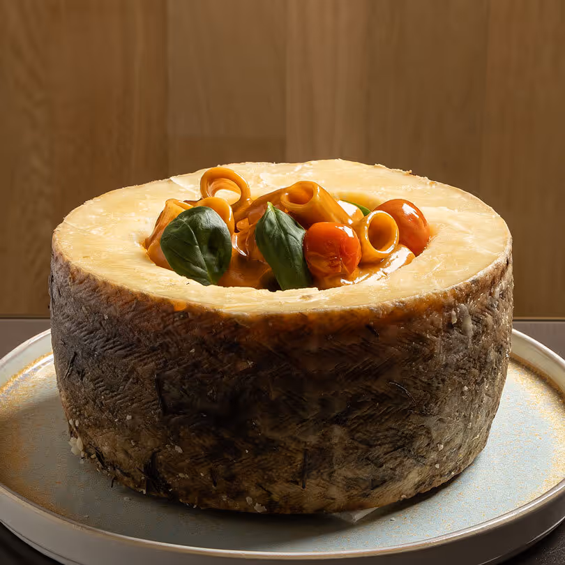 Queso redondo con tomates cherry y hojas verdes en la parte superior