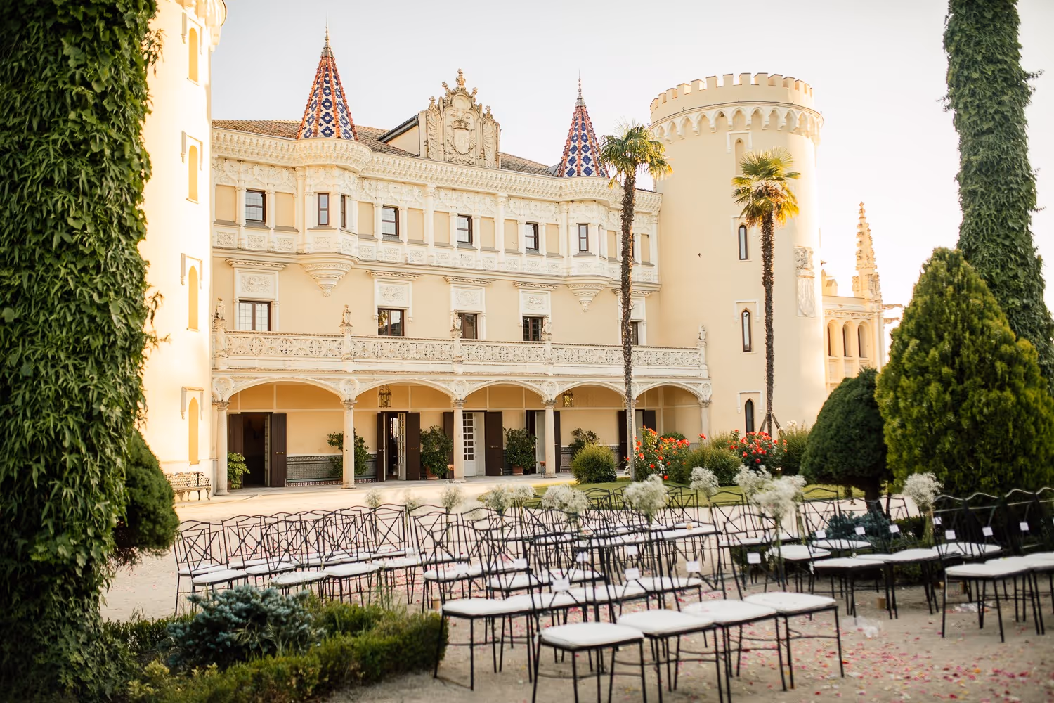 Palacio elegante con torres, jardines y sillas preparadas para un evento