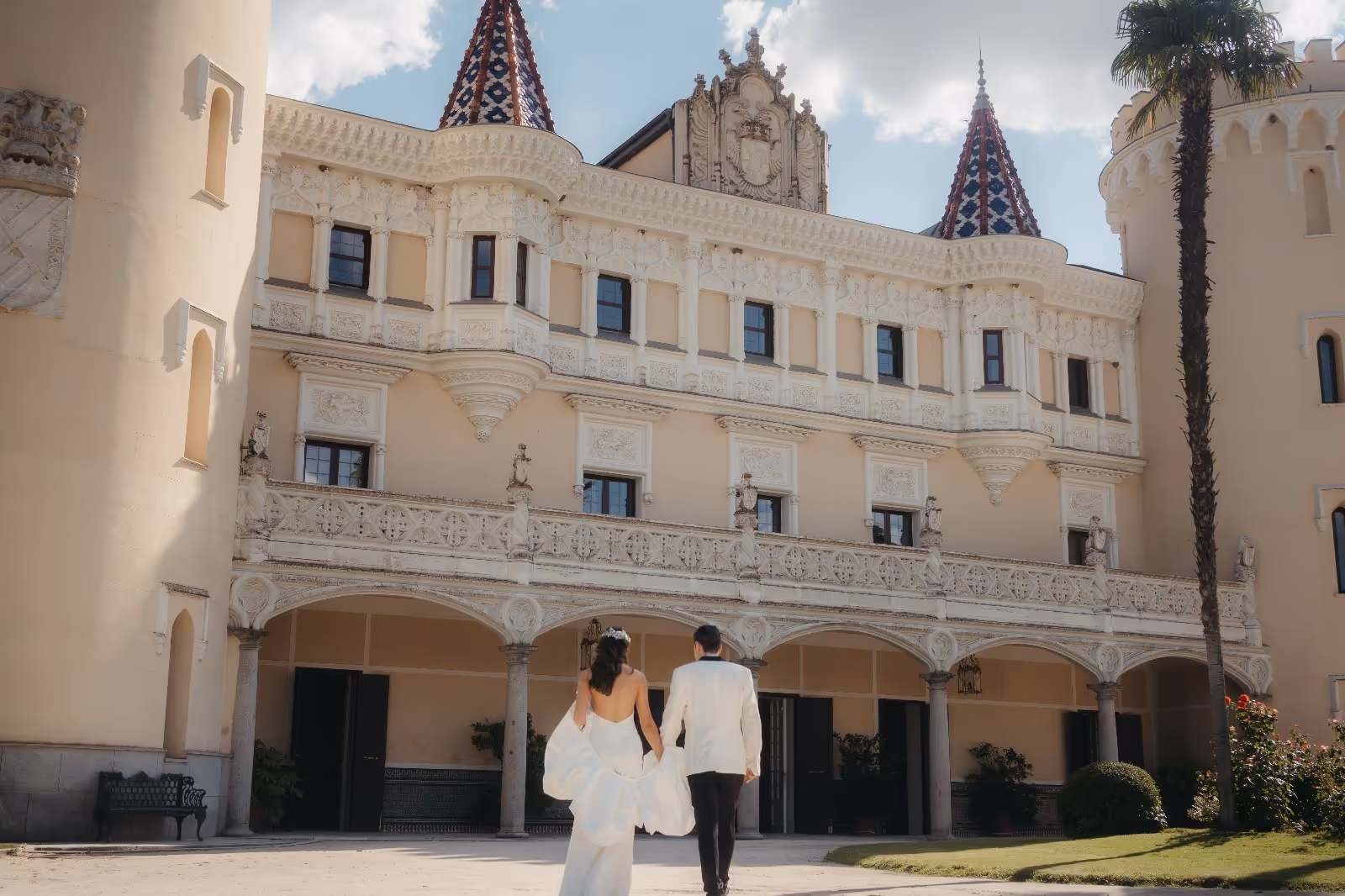 Pareja de novios frente a un elegante palacio con arquitectura ornamentada