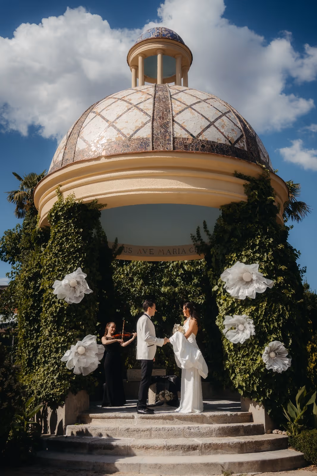 Boda bajo pabellón con cúpula de mosaico, flores blancas y vegetación