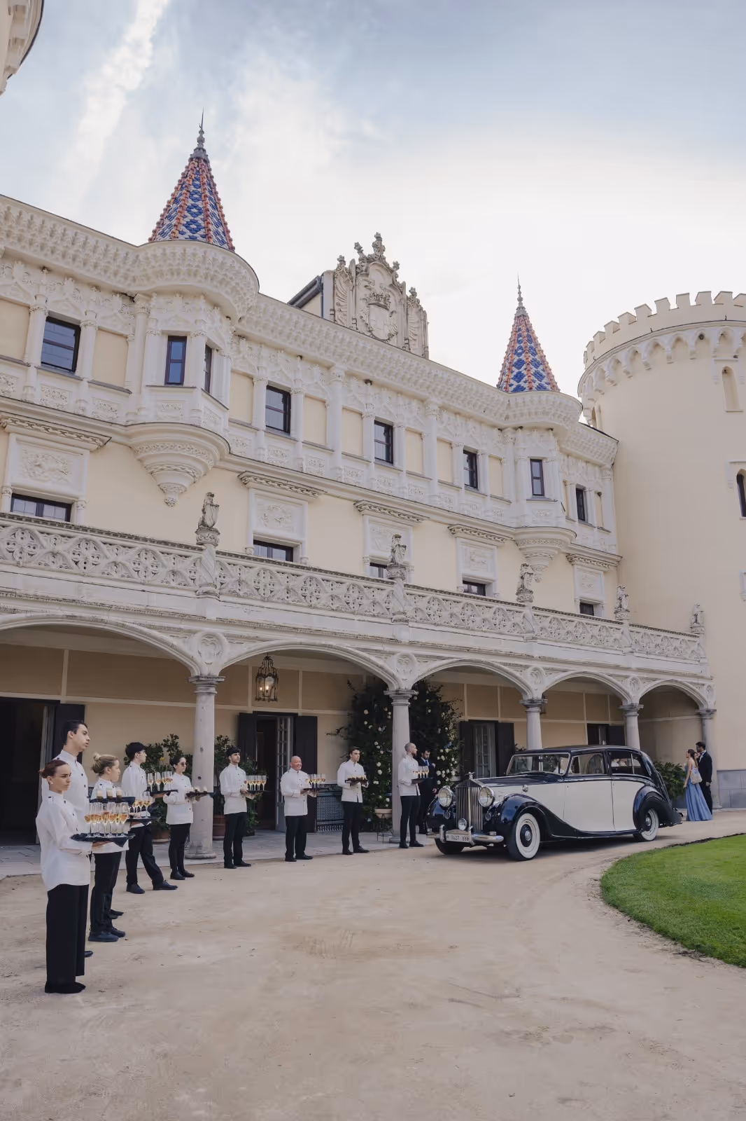 Palacio elegante con personal de servicio, coche vintage y arquitectura señorial