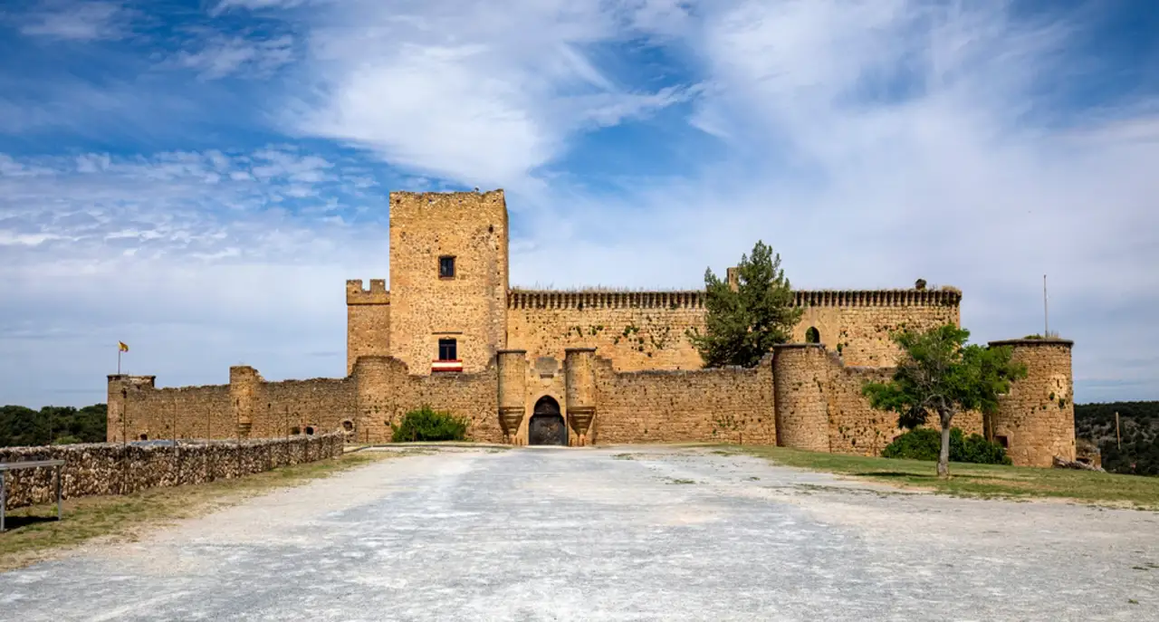 Castillo medieval de piedra con murallas bajo un cielo azul nublado