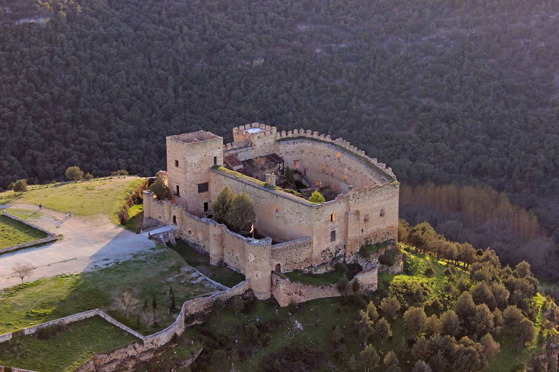 Castillo medieval de piedra rodeado de bosque denso en paisaje verde