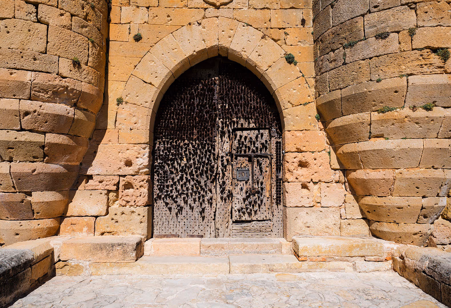 Puerta antigua de piedra con arco ojival y elaborada reja metálica