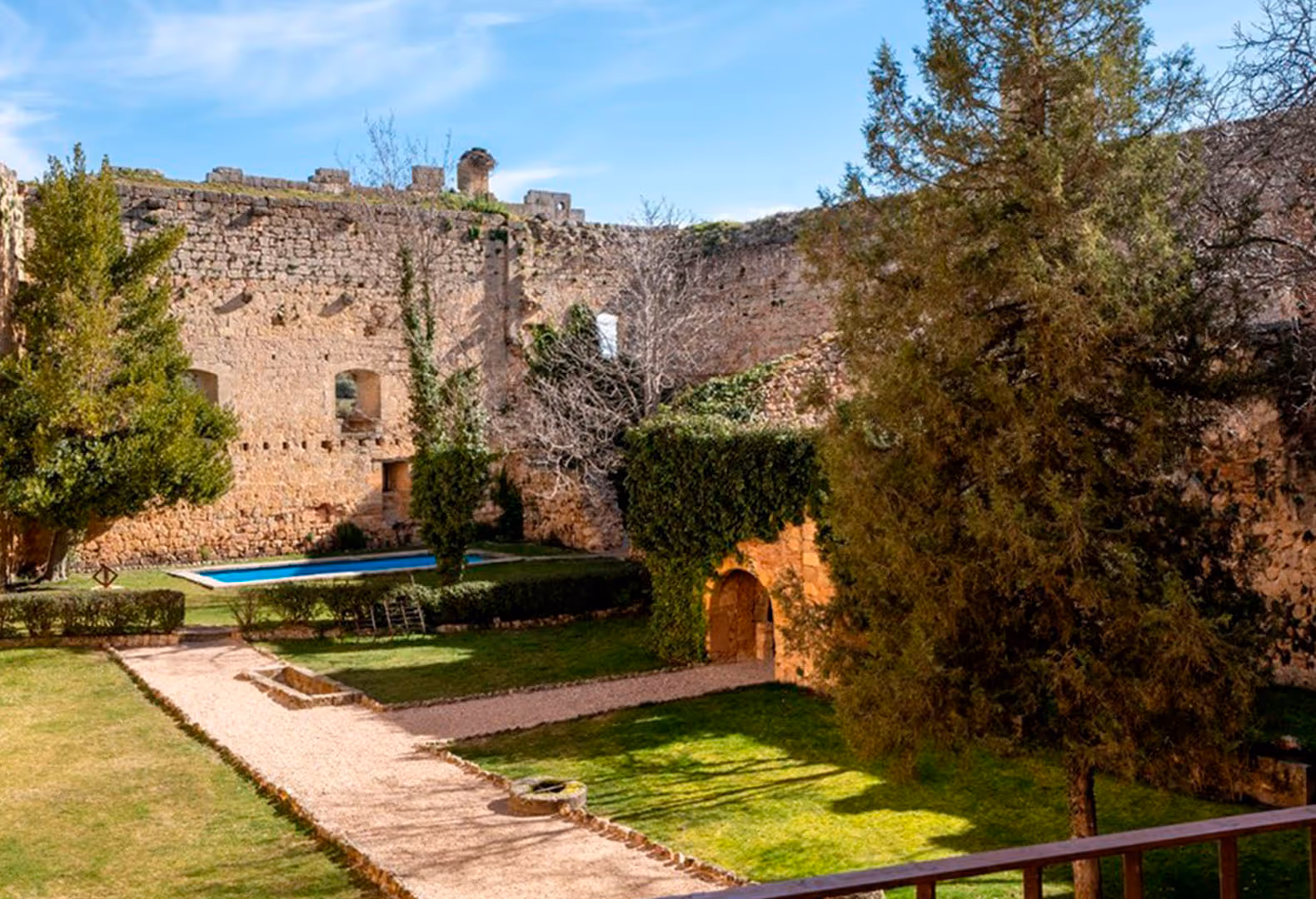 Castillo antiguo con piscina y jardines verdes en un día soleado