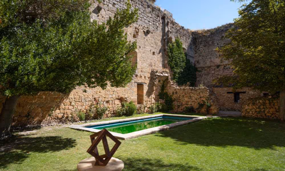 Piscina moderna en un patio de castillo antiguo con jardín verde